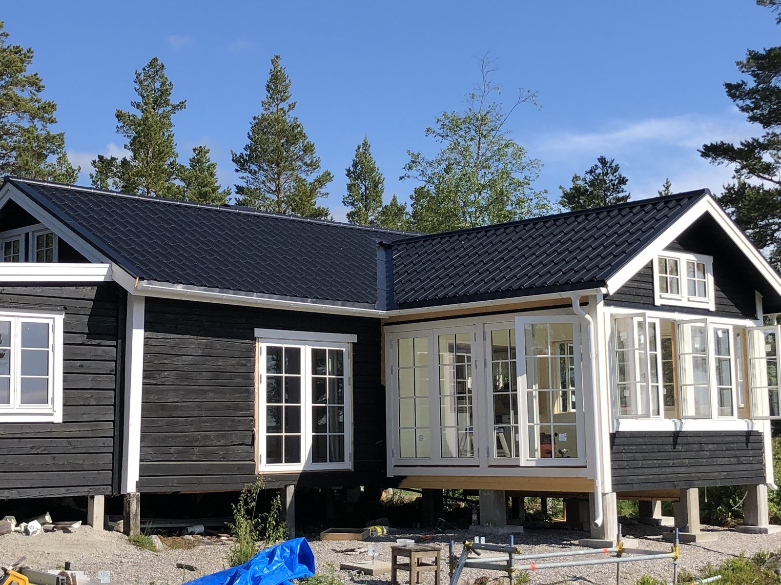 Svart fritidshus med nytt plåttak och vita spröjsade fönster, Norrfjärden